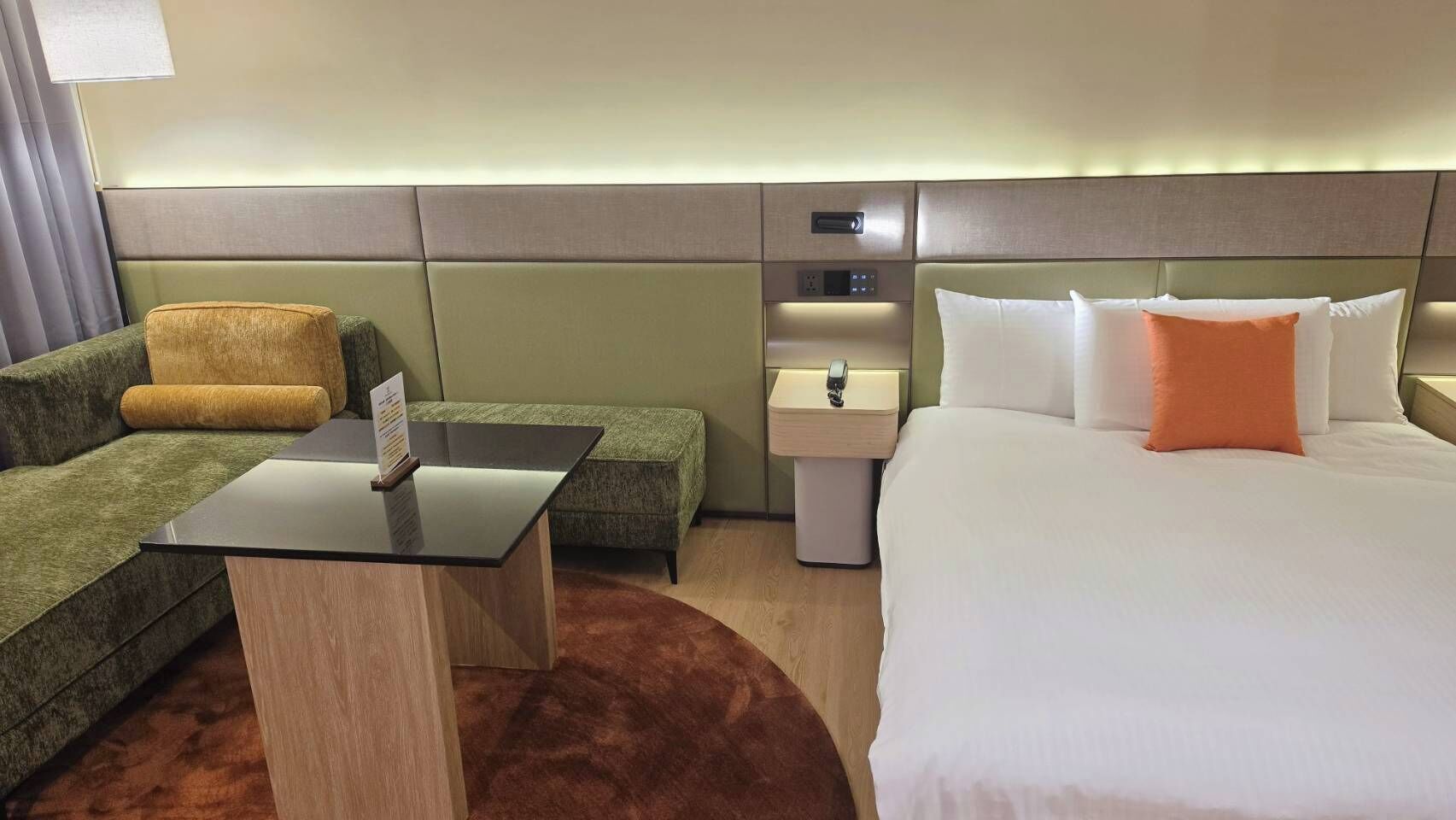 Une chambre d’hôtel avec un lit, un canapé, une petite table et une table de chevet.