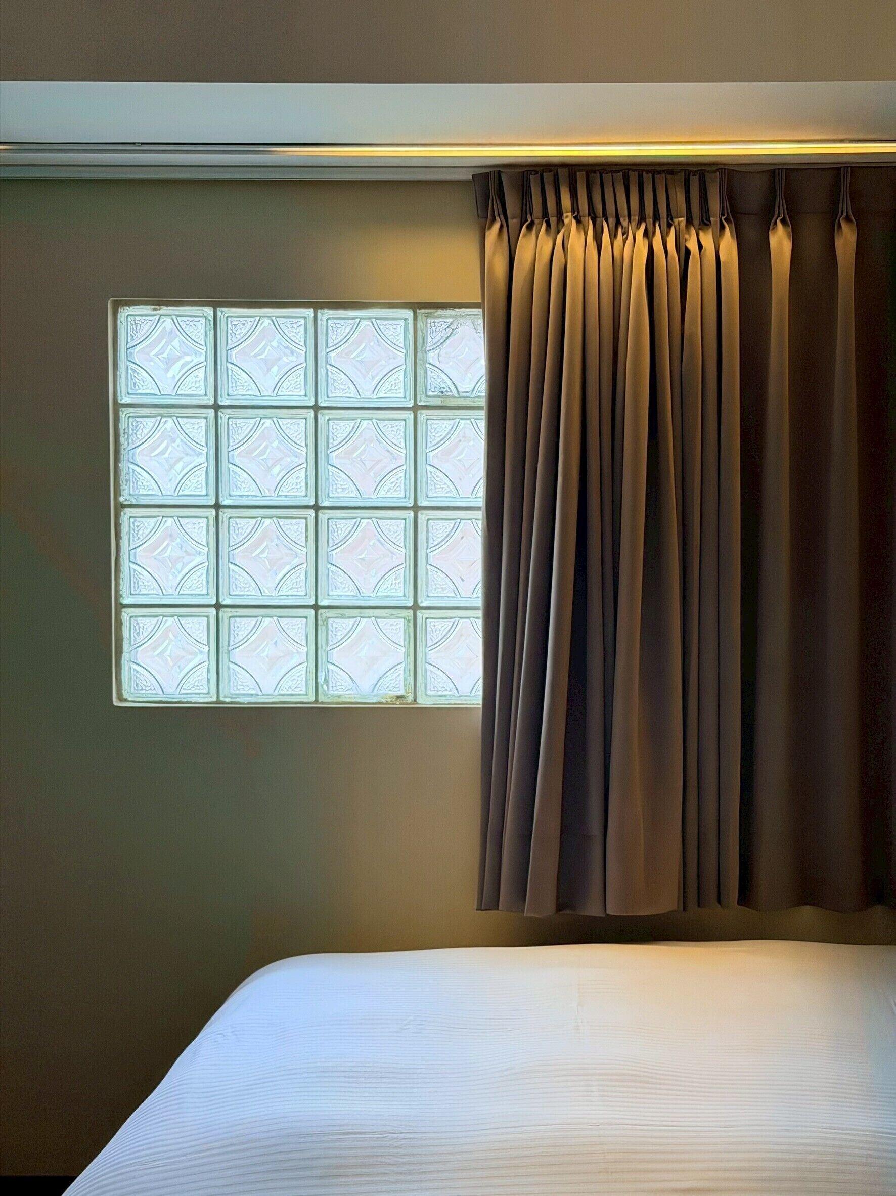 Une chambre à coucher avec un lit, une fenêtre ornée de vitraux et un rideau.