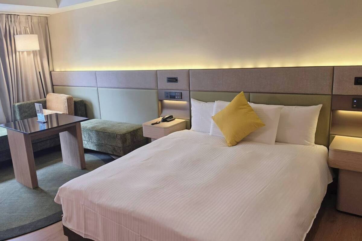 Une chambre d’hôtel comprenant un lit, des tables de chevet, un bureau, une chaise et une lampe.