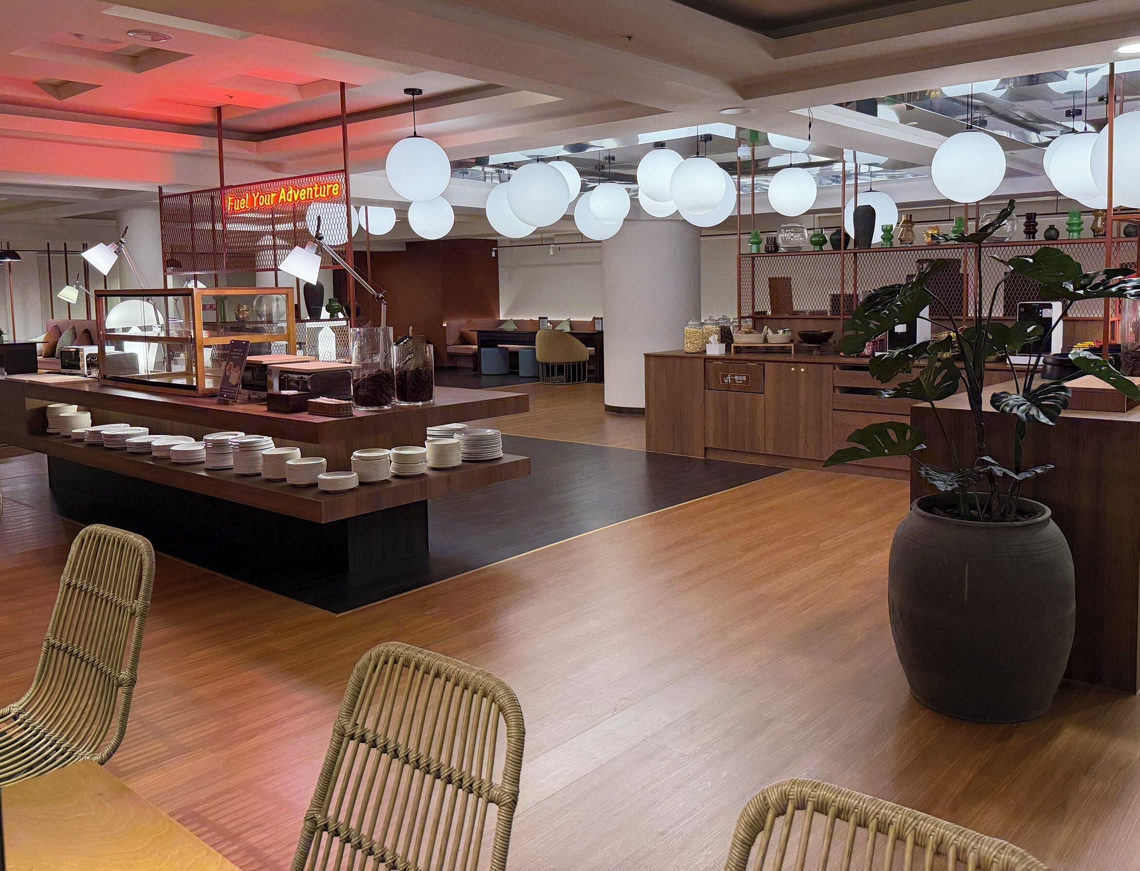 Ein modernes Interieur mit einer Rezeption, einer Essecke und einer großen Topfpflanze.