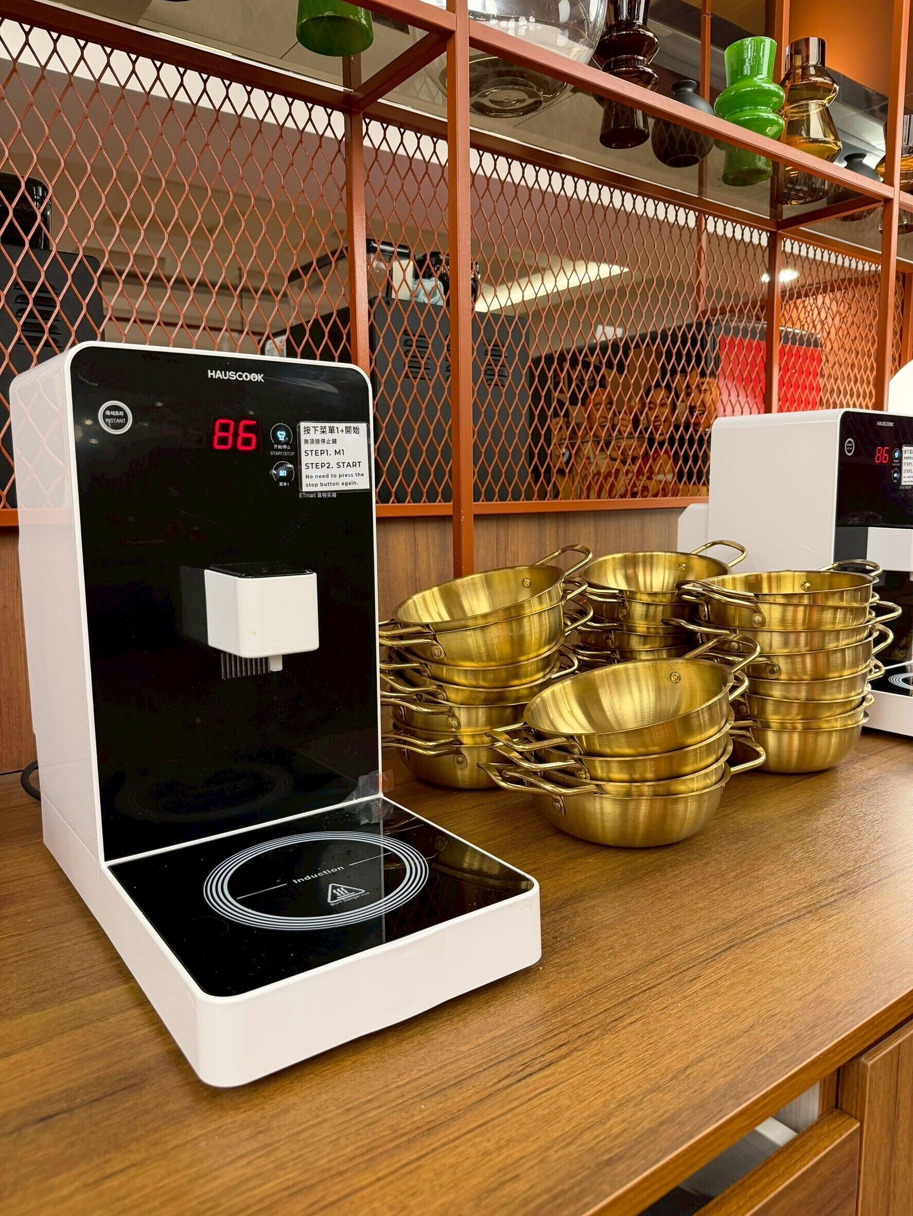 A kitchen with a modern induction cooktop, a digital display, and a set of brass cookware.
