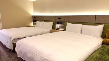 A hotel room with two beds, a nightstand, a lamp, and a green chair.