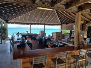 Eine Außenbar mit Meerblick, Holzmöbeln und einer Bar.