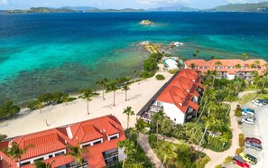Ein Hotel an der Küste mit Gebäuden mit roten Dächern, einem Sandstrand und freiem Blick auf den Ozean.