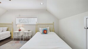 A bedroom with two single beds, a bedside table with a lamp, a window with blinds, and a door. - Bon Villa 102-Golf Cart + Private Pool-Sleeps 10 (Seagrove Beach)