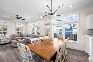 A spacious living room with a wooden dining table, a gray sofa, patterned chairs, and a ceiling fan. - Bon Villa 102-Golf Cart + Private Pool-Sleeps 10 (Seagrove Beach)
