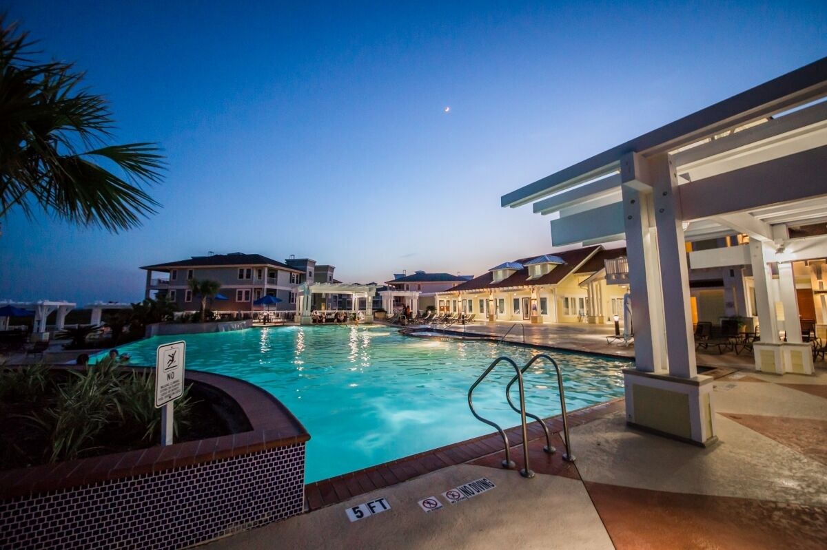 A swimming pool area with a no diving sign, a 5 ft depth marker, and a covered seating area.