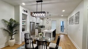 Una cocina moderna con armarios blancos, una isla central e iluminación colgante.