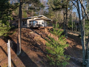 Une cabane dotée d’une terrasse, entourée d’arbres.