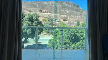 A room with a large window overlooking a hillside with sparse vegetation and a few buildings.