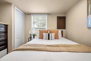 A bedroom with a bed, a window, a door, and a cabinet. - Woodland Peak Tiny Lodge (Woodland Park)