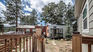 A residential area with a wooden deck, a red house, and a mobile home. - Woodland Peak Tiny Lodge (Woodland Park)