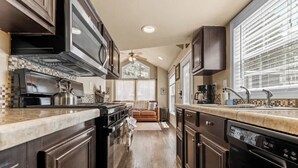 A kitchen with dark wooden cabinets, a stainless steel stove, and a dishwasher. - Woodland Peak Tiny Lodge (Woodland Park)