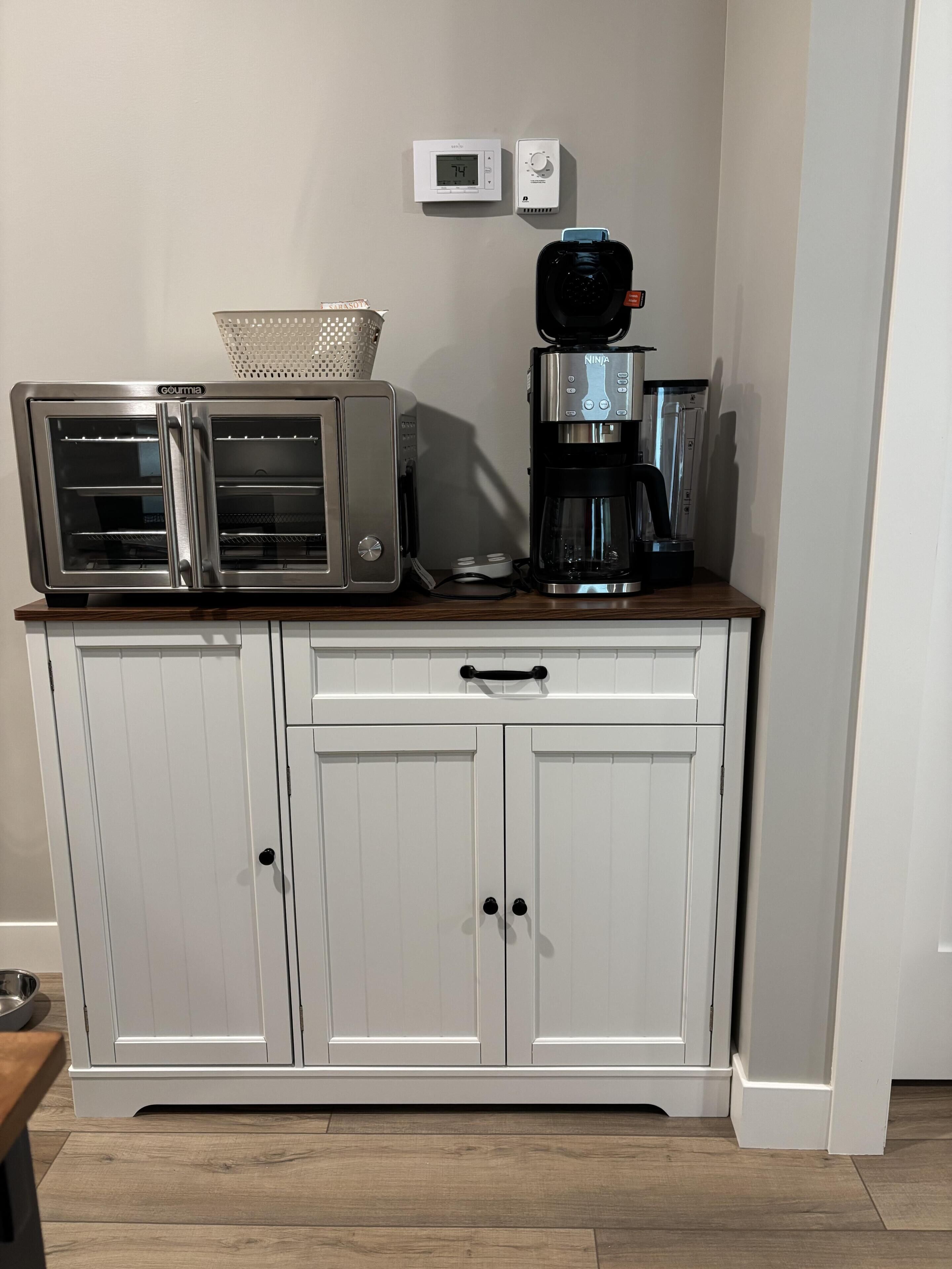 Una kitchenette con horno tostador, cafetera y microondas sobre una encimera de madera.