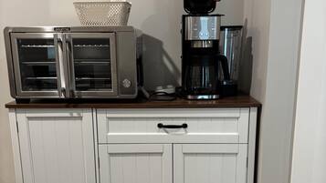 Una kitchenette con horno tostador, cafetera y microondas sobre una encimera de madera.
