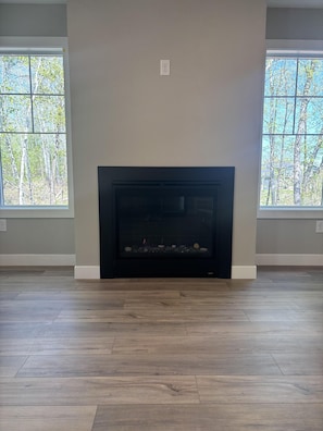 A room with a fireplace, large windows, and wooden flooring. - RiverWest Trailside Tranquility - Sauna - Dogs Friendly (Duluth)
