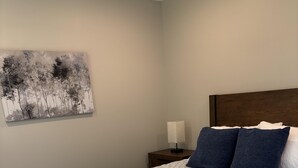 Een net opgemaakt bed met een gewatteerde spreideken, twee kussens en opgevouwen handdoeken.