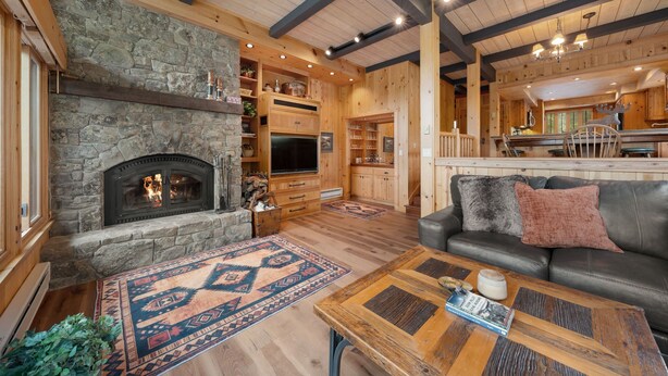 Una sala de estar acogedora con chimenea de piedra, vigas de madera y sofá de cuero.