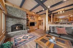Ein gemütliches Wohnzimmer mit Kamin aus Stein, Holzbalken und einem Ledersofa.