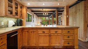 Una cocina amplia con armarios de madera, una isla grande y un protector contra salpicaduras de piedra.