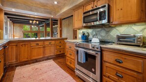 Una cocina con armarios de madera, electrodomésticos de acero inoxidable y un ventanal grande.