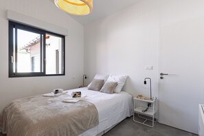 A bedroom with a bed, a window, a door, and a bedside table. - Cozy Cottage with Spa - Welkeys (Moliets-et-Maa)