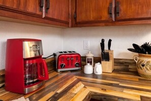 Eine Küche mit einer roten Kaffeemaschine, einem Toaster, einem Messerblock und einer dekorativen Karaffe auf der Arbeitsfläche.