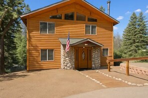 Eine zweistöckige Holzhütte mit Steinunterbau, einer Veranda und einer amerikanischen Flagge.