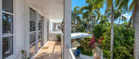 A balcony with a view of palm trees and a tiled floor.