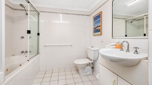 A bathroom with a bathtub, toilet, sink, and a shower. - Heart of Townsville on the Harbour (Townsville City)