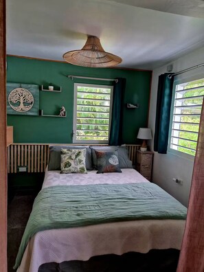 Ein Schlafzimmer mit Bett, einer Hängelampe, einem Fenster mit Vorhängen, einem Wandregal und einer dekorativen Baumskulptur.