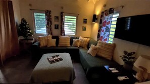 Uma sala de estar com sofá, banquinho e árvore de Natal.