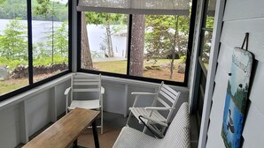 A covered porch with a bench, a white sofa, and a view of a lake.