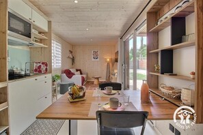 Een kleine keuken met een eethoek, houten kastjes en een groot raam.
