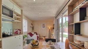 A compact kitchen with a microwave, stove, and dining area with a table set for two. - Ker Lann - TREBEURDEN (TREBEURDEN)