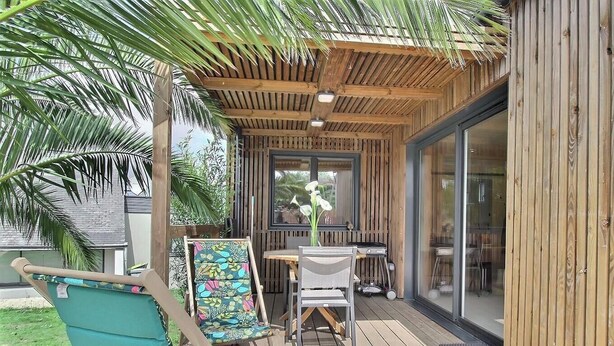 A covered outdoor seating area with a table and chairs, a hammock, and a grill. - Ker Lann - TREBEURDEN (TREBEURDEN)
