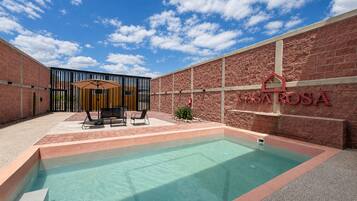Une piscine avec un espace patio, un mur en briques et une enseigne indiquant « CASAROSA ».