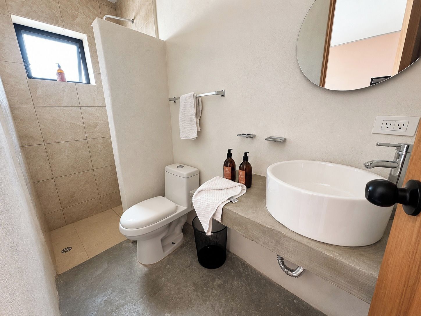 Un baño moderno con inodoro, bidé, lavamanos y una pequeña ventana.