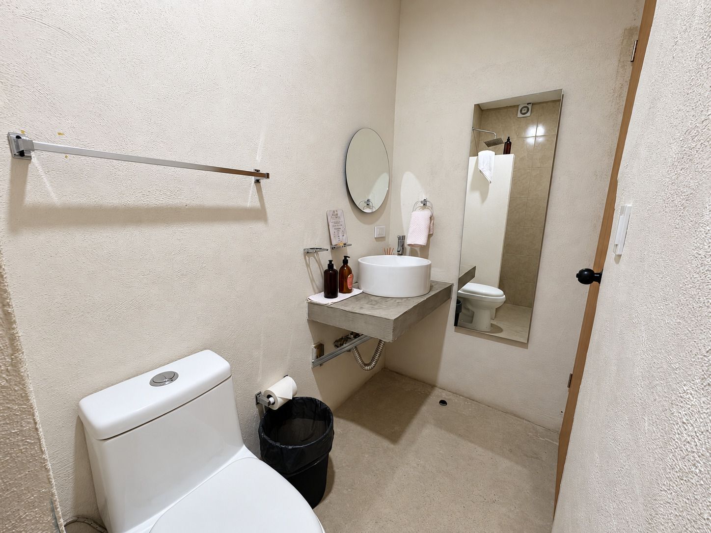 A compact bathroom with a toilet, sink, mirror, and a shower area.
