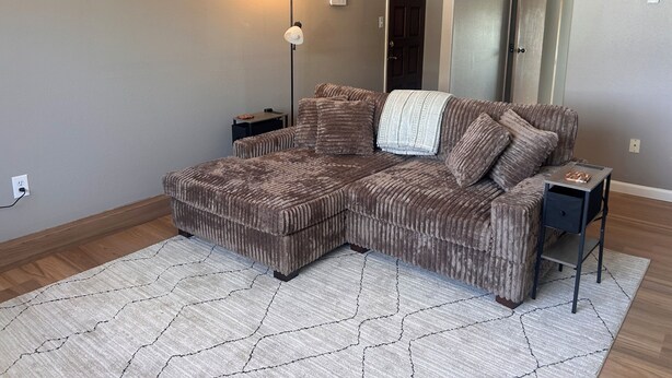 Una sala de estar con un sofá modular, una lámpara de pie, una mesita y una alfombra.