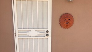 Una puerta con mosquitera, una lámpara de pared y un felpudo con la palabra 'HELLO'.