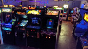 A row of arcade machines with various games, including titles like 'Tron' and 'Tetris.'