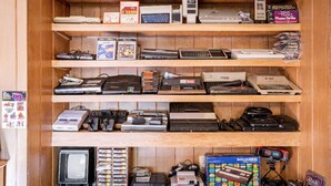 A wooden shelf with various electronic devices and games.