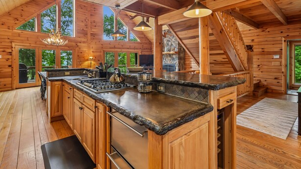 A spacious wooden cabin interior with a large kitchen island, built-in appliances, and a stone accent wall. - Escape to Summit View Lodge in Mountaintop, a spacious pet-friendly retreat for 14! (McHenry)