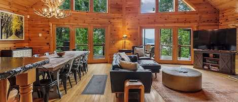 A spacious wooden cabin with a dining area, living room, and large windows offering views of the outdoors.