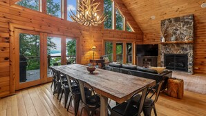 A spacious cabin with a large dining table, multiple chairs, a fireplace, and a stone accent wall. - Escape to Summit View Lodge in Mountaintop, a spacious pet-friendly retreat for 14! (McHenry)