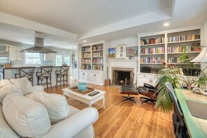 Ein großzügiger Wohnbereich mit Kamin, Bücherregalen, einer Couch und einem Essbereich.