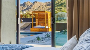 A bedroom with a large window, a bed, and a view of a pool and mountains. - Skyhaven Luxe - Pool/Spa Pickleball Sauna (Joshua Tree)
