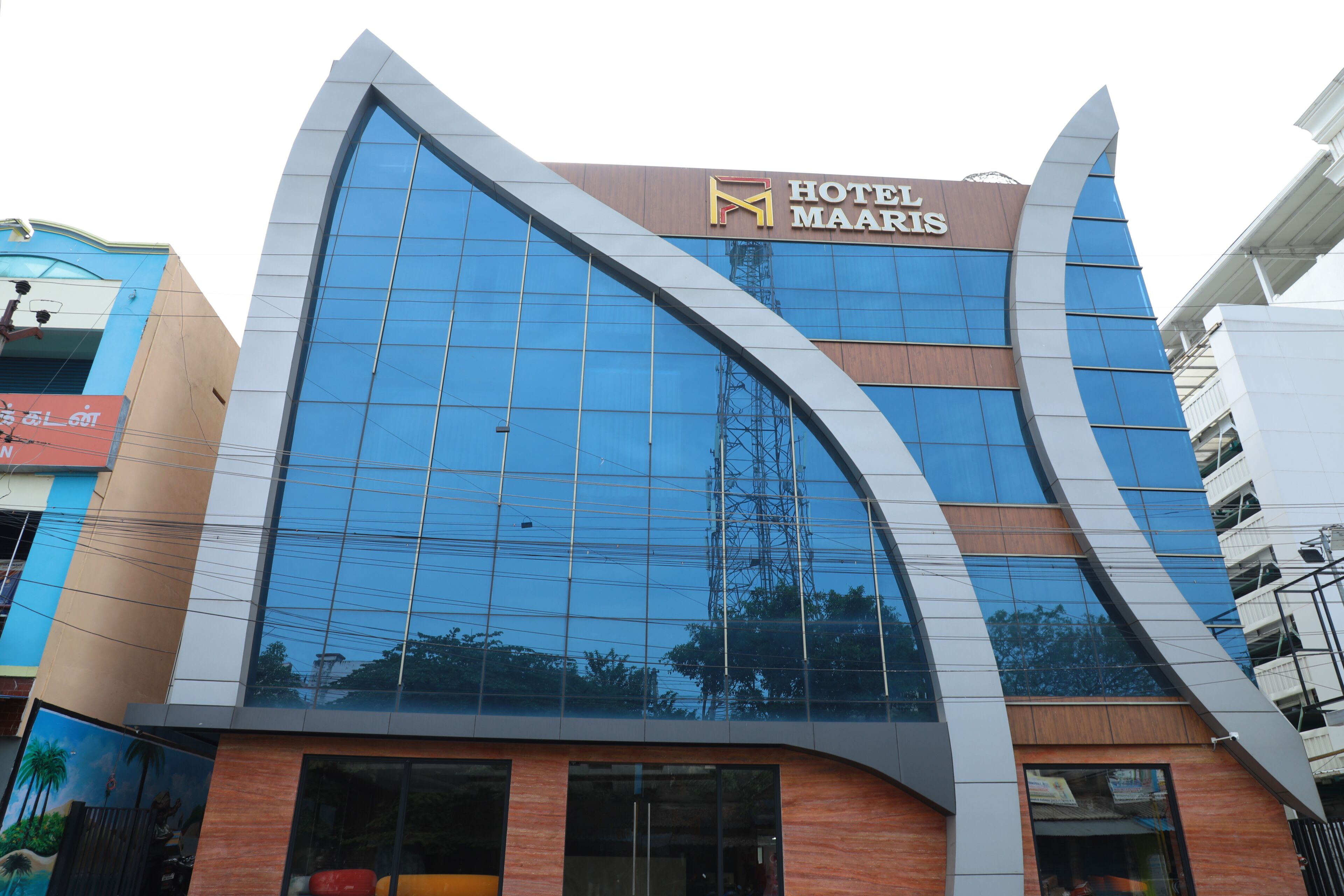 A modern hotel building with a prominent curved glass facade and a sign reading 'HOTEL MAARIS'.