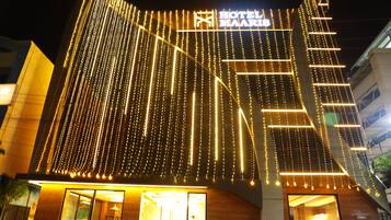 A hotel with a modern facade, illuminated string lights, and a prominent sign.